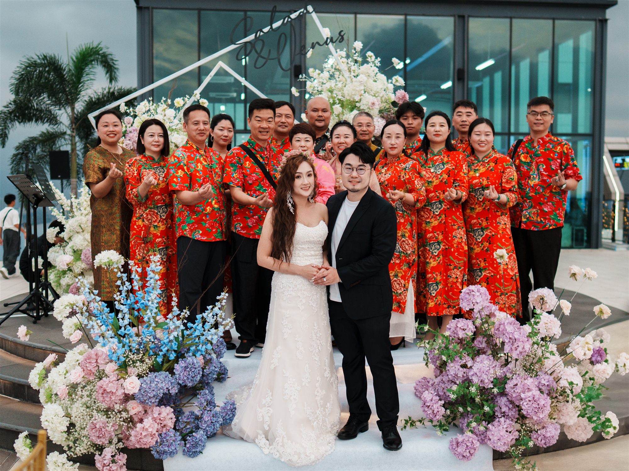 Couple with family at floral arch outdoor wedding ceremony