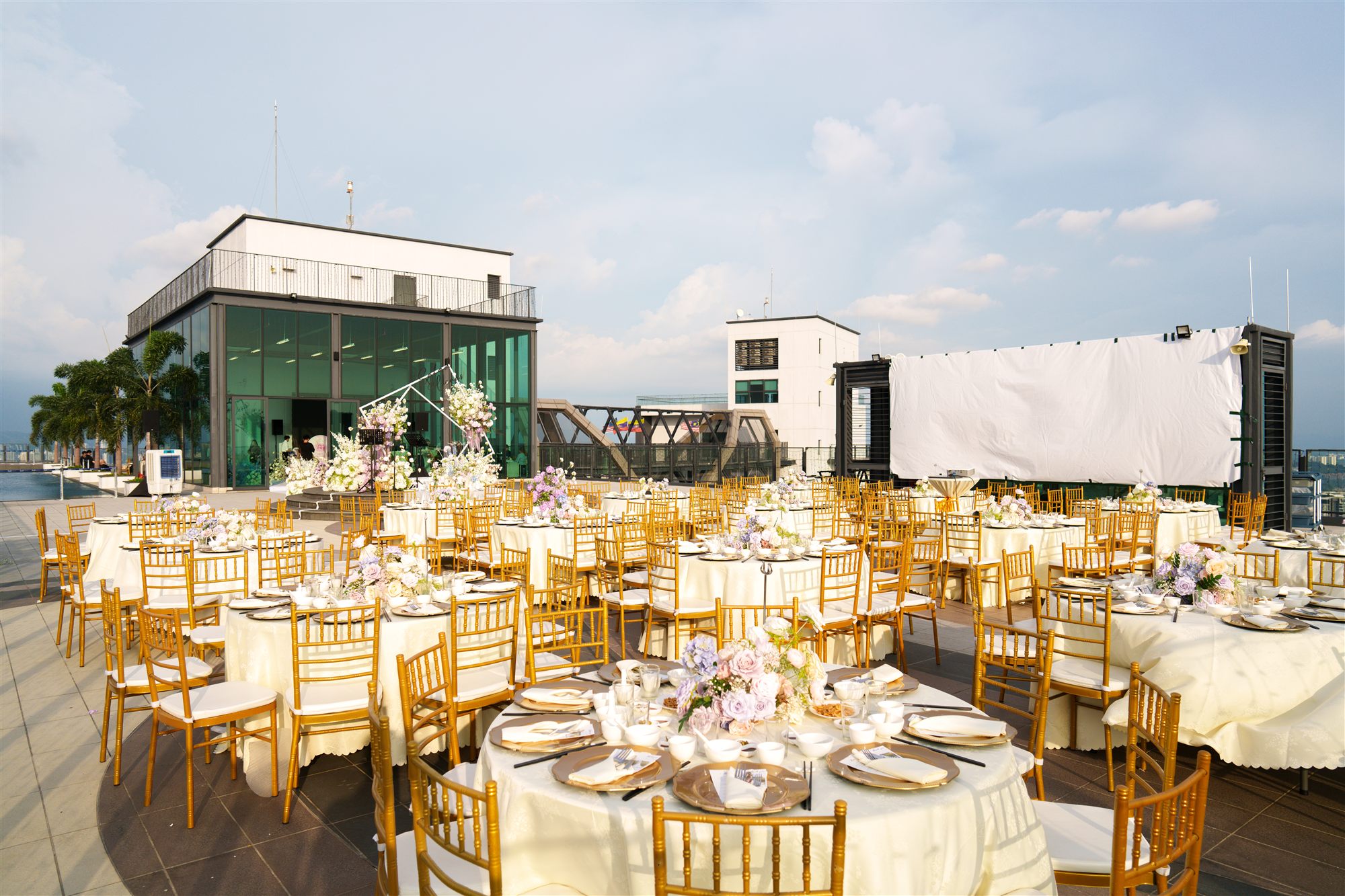 Rooftop wedding reception tables with gold chiavari chairs and floral centrepieces